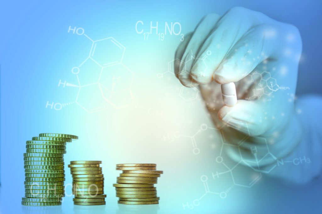 medicine industry concept blue background hand holding drug with coin stacks and medicine formulas