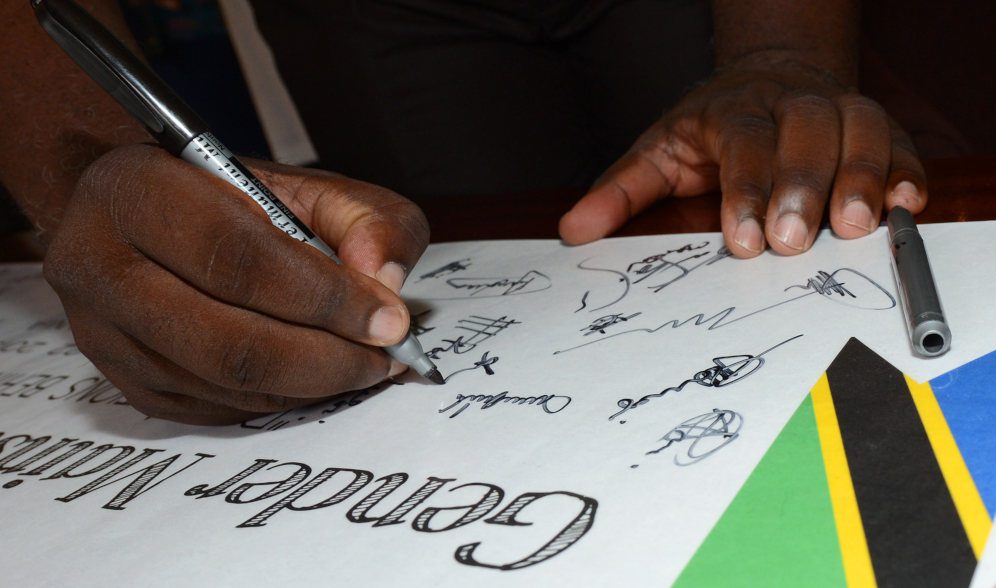 An event participant signing Gender Mainstreaming Seminar in Tanzania, Africa signs an event banner on May 18, 2015.

More:

 United States Army Africa (USARAF) co-hosted the conference, along side the Tanzanian Peoples Defense Force, in an effort to frame the importance of gender mainstreaming and promote equality throughout the region. (DoD News photo by SSgt Brian Kimball). Original public domain image from Flickr