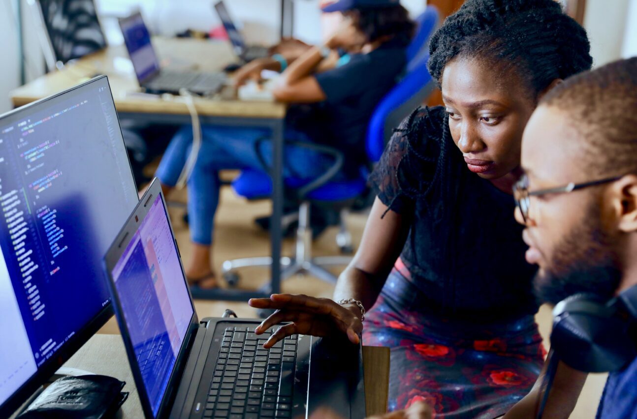 Two individuals collaborating on a computer in an office - gender transformation in science, technology and innovation