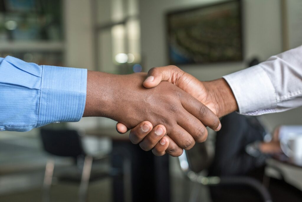 Two professionals shaking hands during a meeting, representing collaboration and partnership.